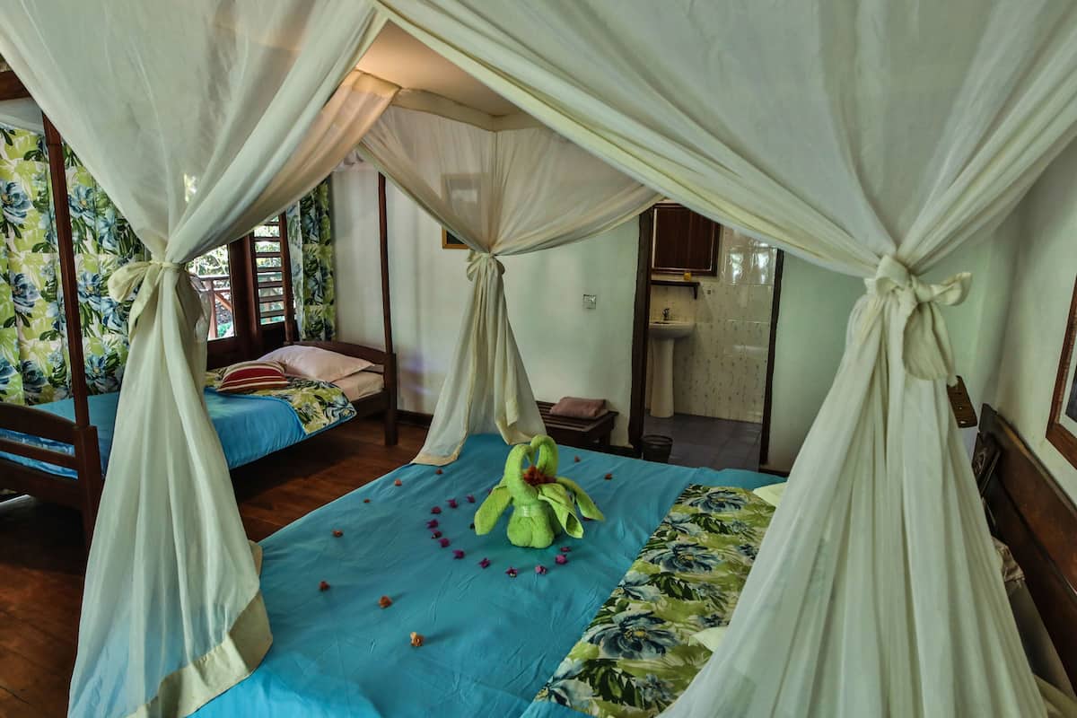 Ein Zimmer mit einem Himmelsbett, einem kleinen Tisch und Blick auf ein Badezimmer.