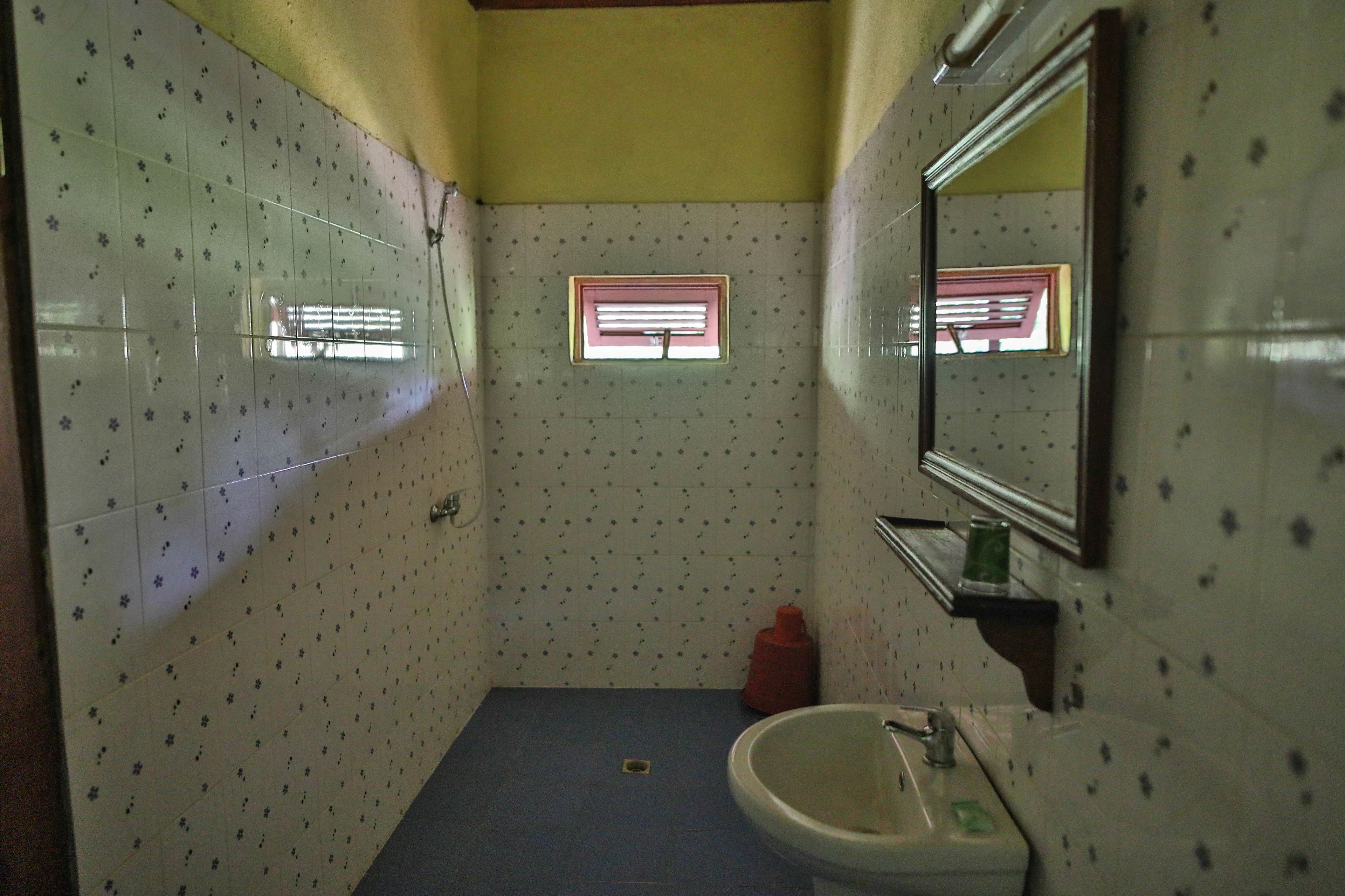 A small bathroom with a sink, mirror, and window.