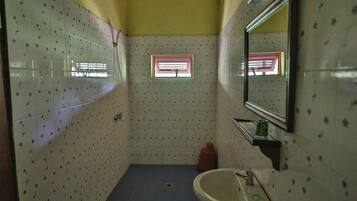 A small bathroom with a sink, mirror, and window.