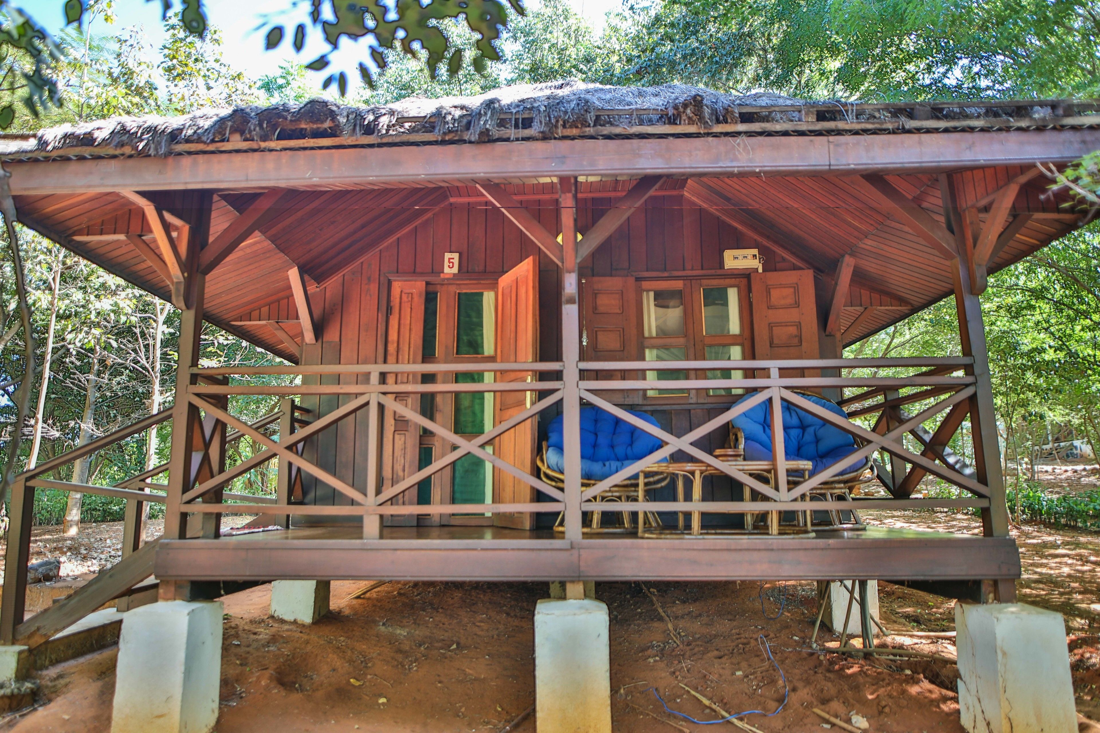 A wooden cabin with a thatched roof, a porch with a railing, and a number '5' sign.