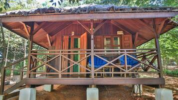 A wooden cabin with a thatched roof, a porch with a railing, and a number '5' sign.