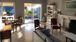 A living room with a sofa, chairs, a fireplace, a bookshelf, and a dining area with a table and chairs. - Comfortable family home a stone's throw from the GR34 and beaches (Crozon)