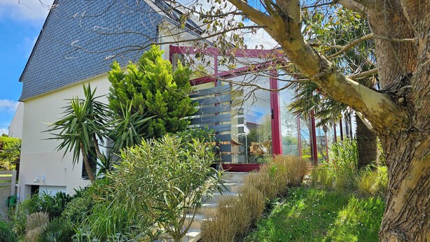 A modern house with a sloped roof, surrounded by lush greenery and a tree. - Comfortable family home a stone's throw from the GR34 and beaches (Crozon)