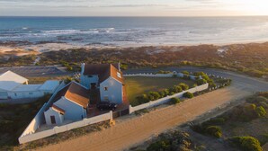 An aerial view of a coastal property with a large house, a driveway, and a sandy beach. - Storkereden (Pearly Beach)