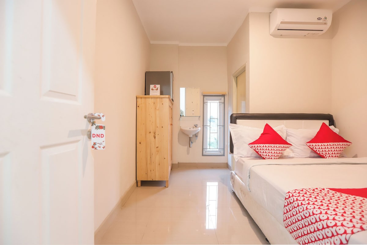Une chambre d’hôtel équipée d’un lit, d’une armoire en bois, d’un lavabo et d’un appareil de climatisation.