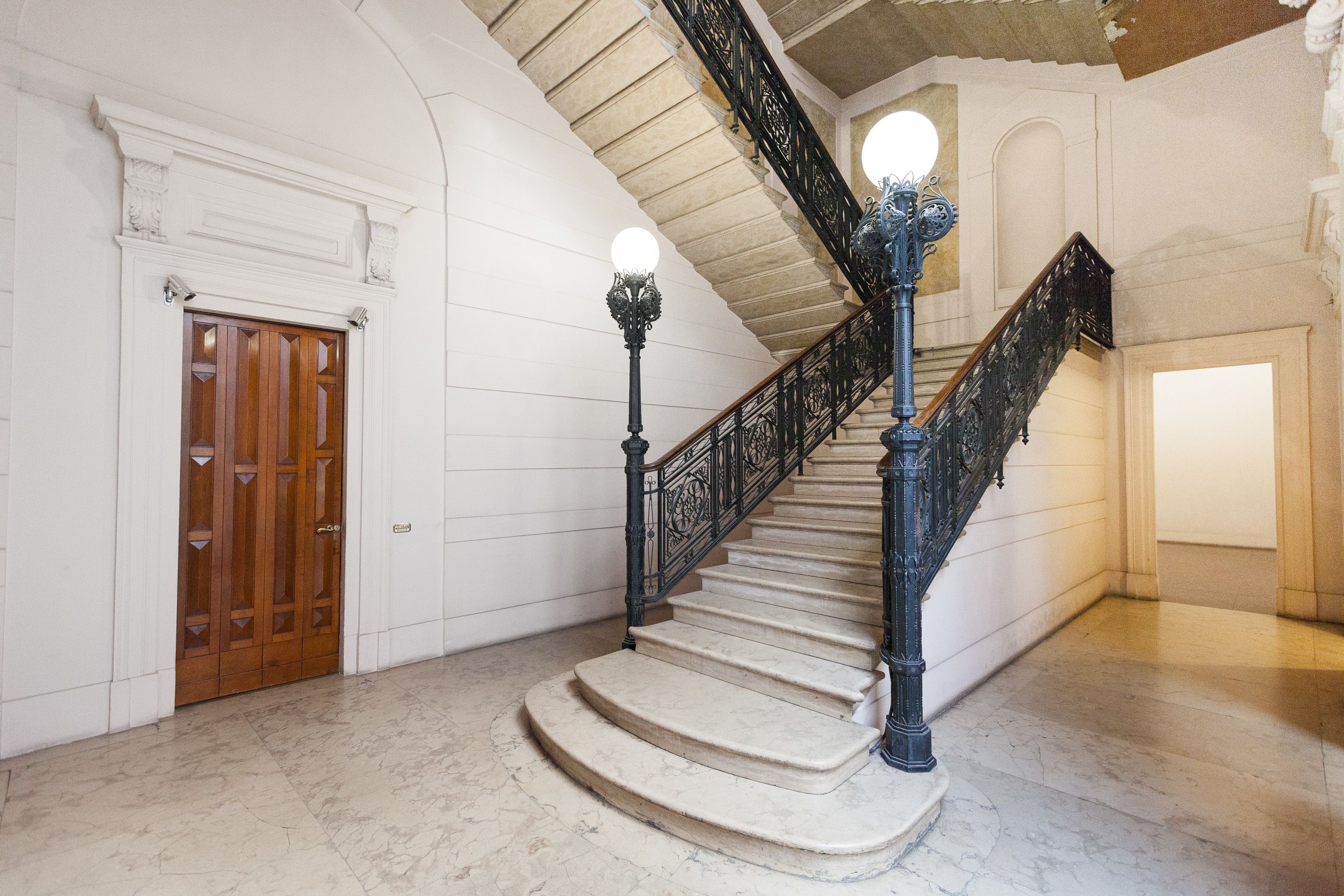 A grand staircase with ornate black railings and a marble floor.