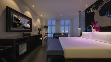 A modern hotel room with a large bed, a flat-screen TV, a desk, and a chair.