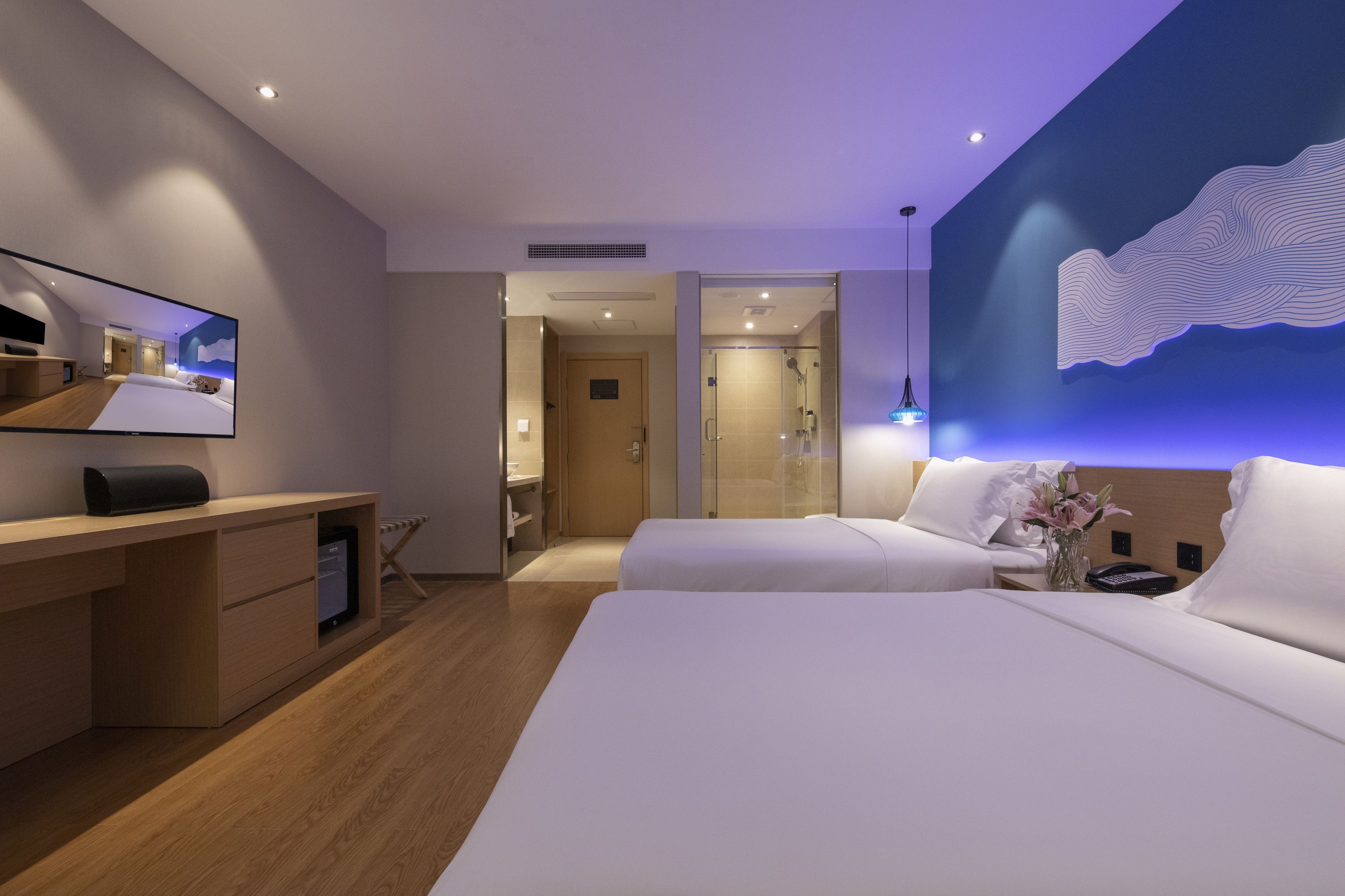 Una habitación de hotel moderna con una cama grande, un escritorio y una zona de ducha.