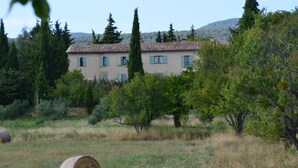 A rustic building with a tiled roof, surrounded by trees and grass.
