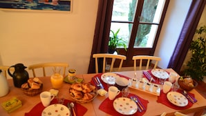 A breakfast table set with plates, cups, and a variety of food items.
