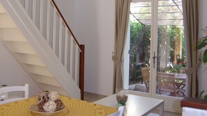 Eine Treppe mit weißen Geländern und einem Holzhandlauf, die zu einem Raum mit Tisch und Stühlen führt.
