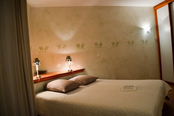 A bedroom with a bed, two bedside lamps, a nightstand, and a mirror.