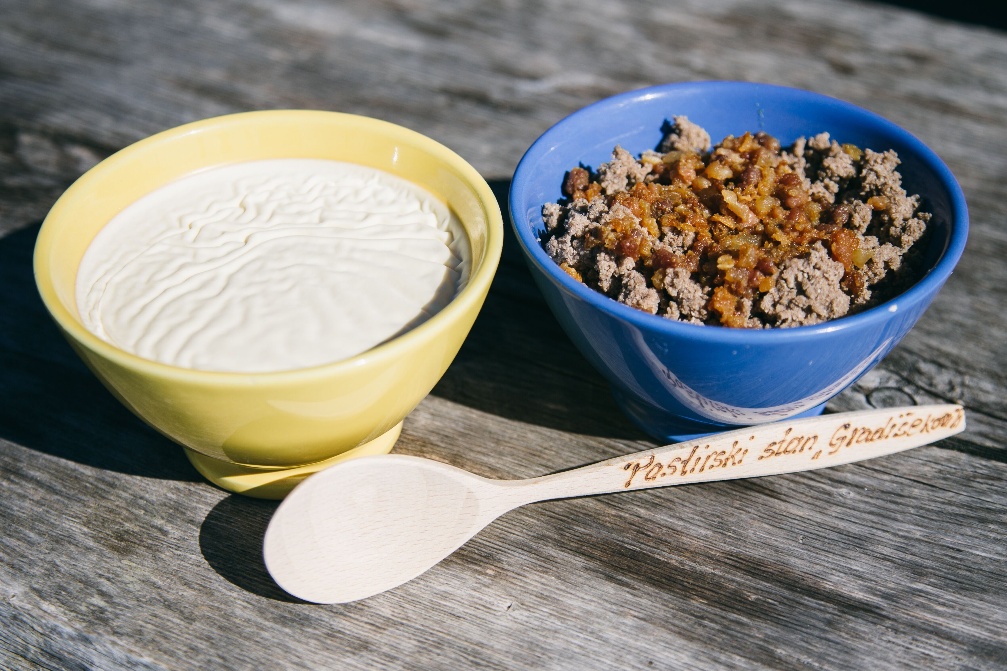 Two bowls of food on a wooden surface.
