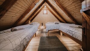 A cozy attic bedroom with two beds, wooden beams, and a small window. - Koca Ojstrica - Velika planina (Kamnik)