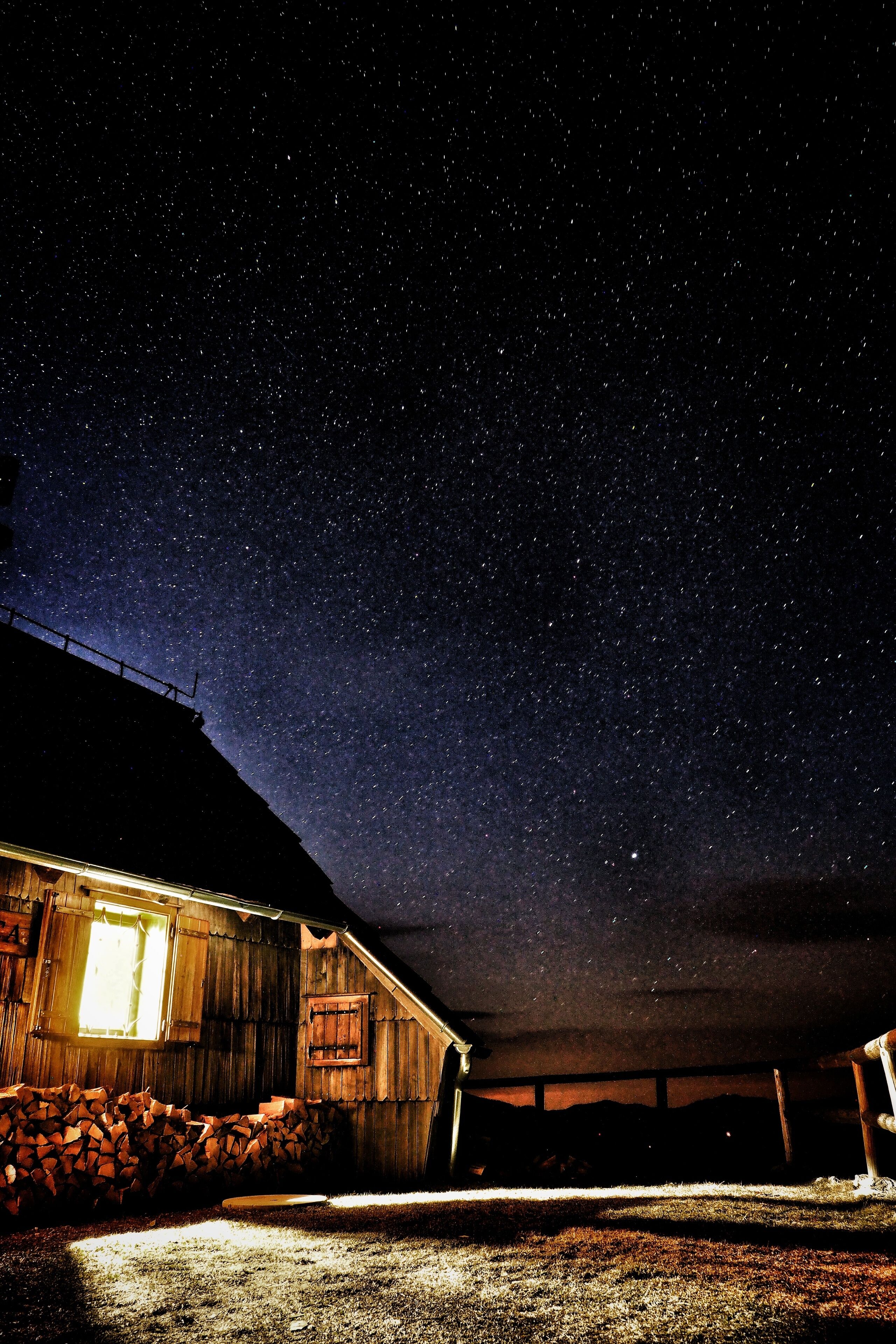 A rustic barn under a starry night sky.