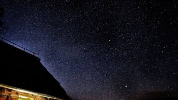 A rustic barn under a starry night sky.