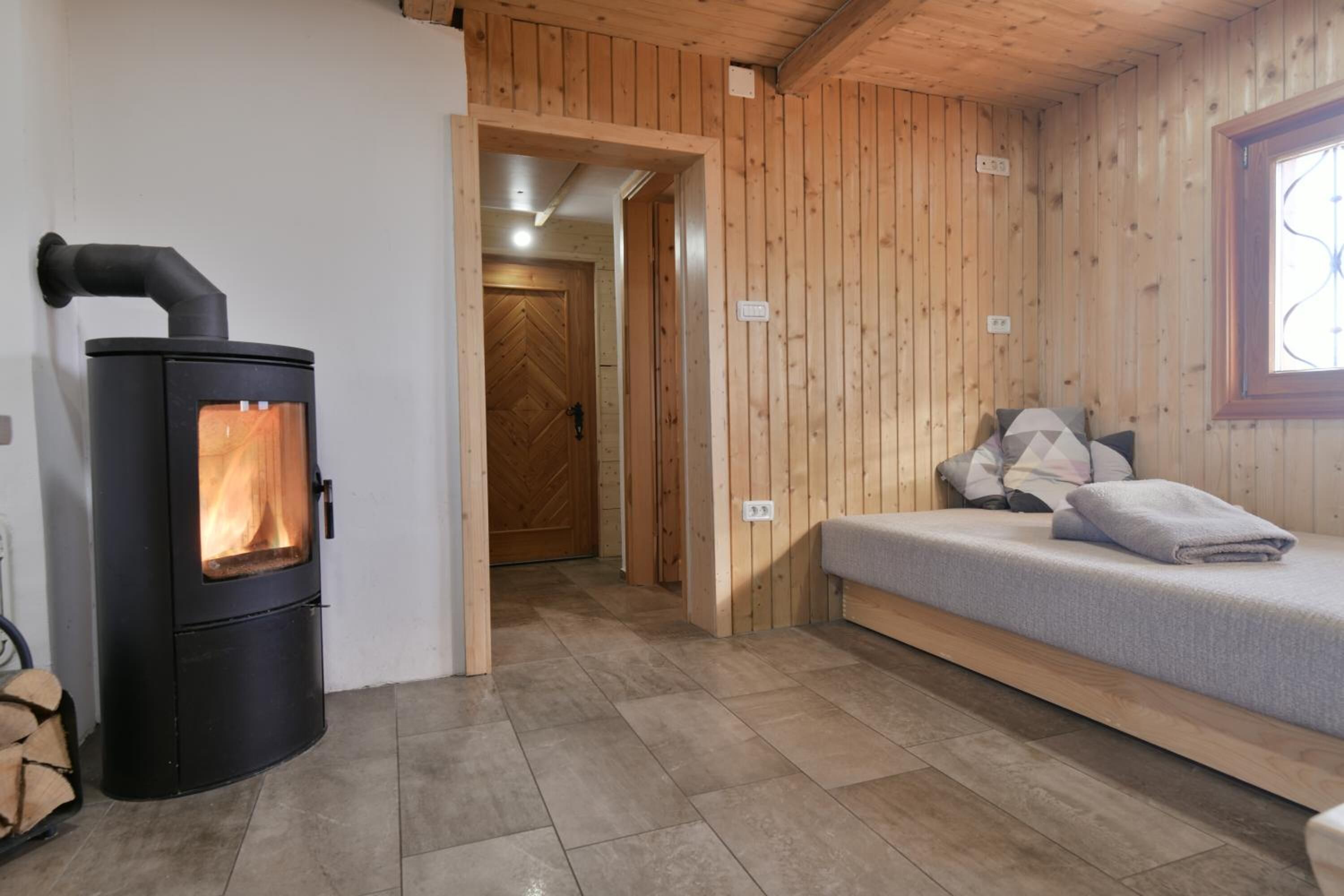 Ein gemütliches Zimmer mit Kaminofen, einem Bett und einer Holzwand.