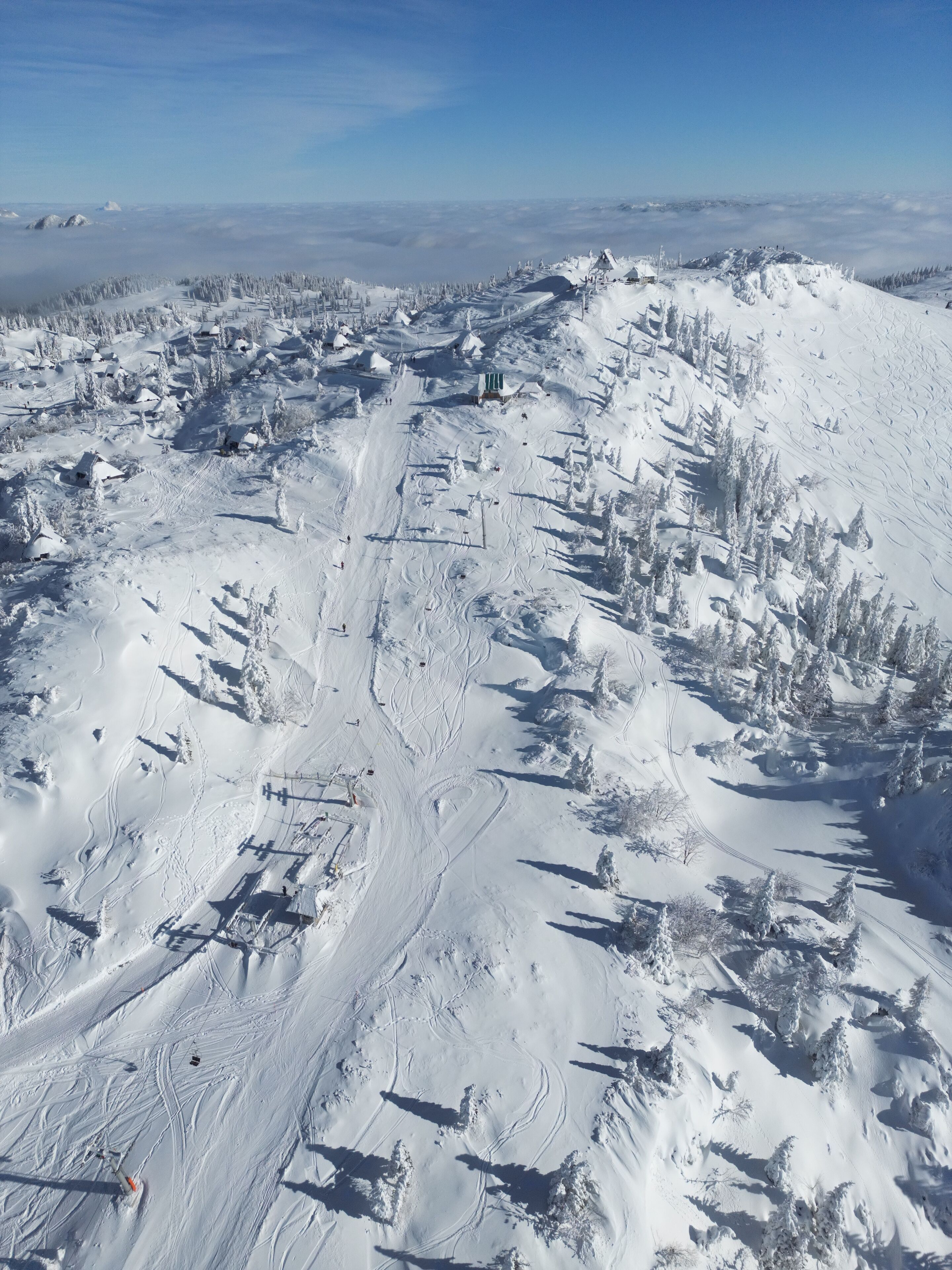 A snow-covered ski resort with ski trails, lifts, and buildings.