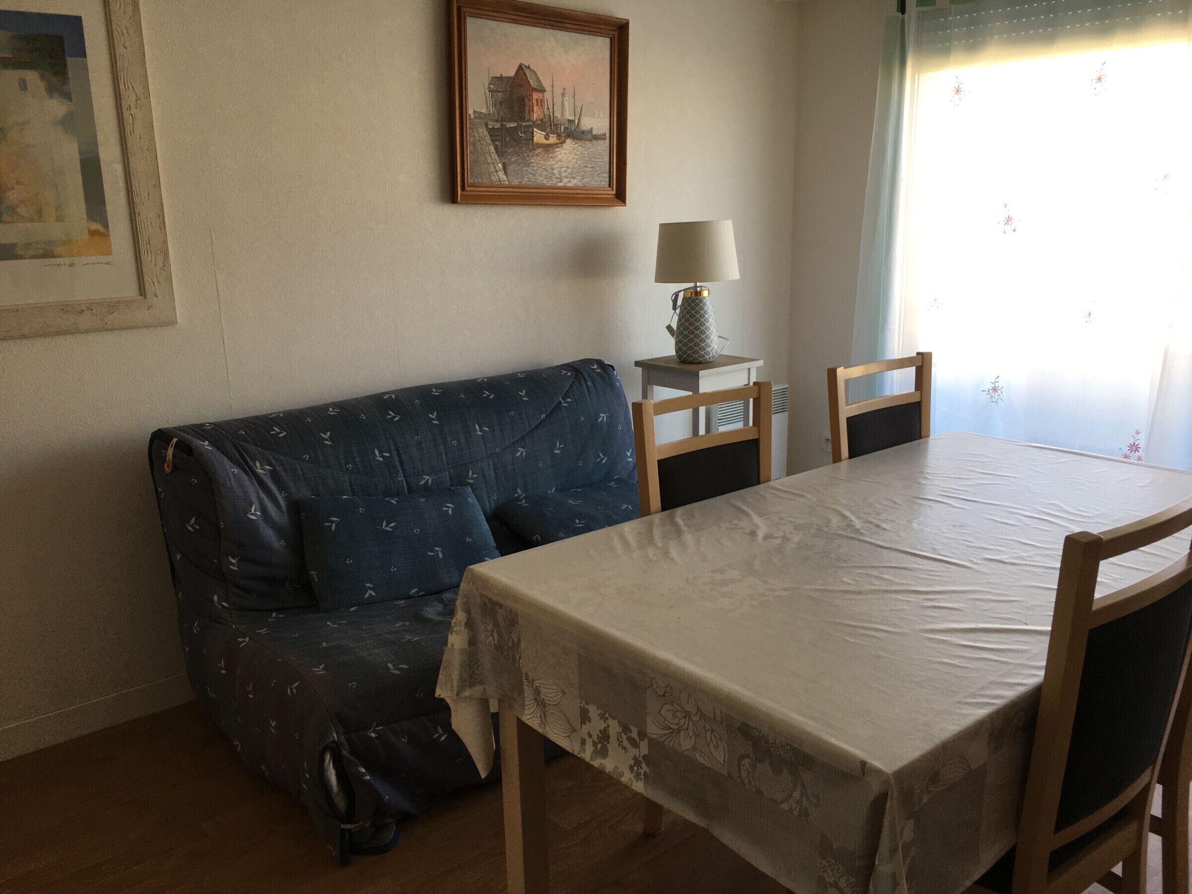 Une pièce avec un canapé, une table et une lampe. Il y a un tableau accroché au mur.