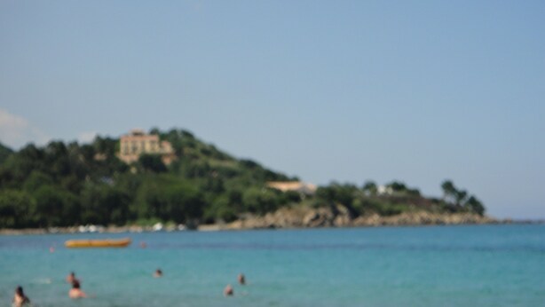 A beach with people swimming, a boat, and a building on a hill in the background. - Mobile home in Figari at the Hamlet of San Gavino (Figari)