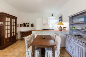 Eine Küche mit einem Holztisch, Stühlen und einem Schrank.