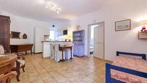 Een ruime woonkamer met keuken, eettafel en een blauw bed.