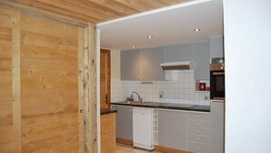 Une cuisine moderne avec des meubles gris, un lave-vaisselle blanc et un plafond en bois.