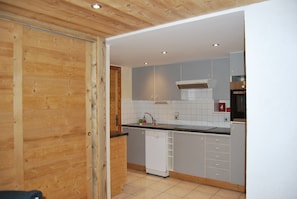Een moderne keuken met grijze kastjes, een witte vaatwasser en een houten plafond.