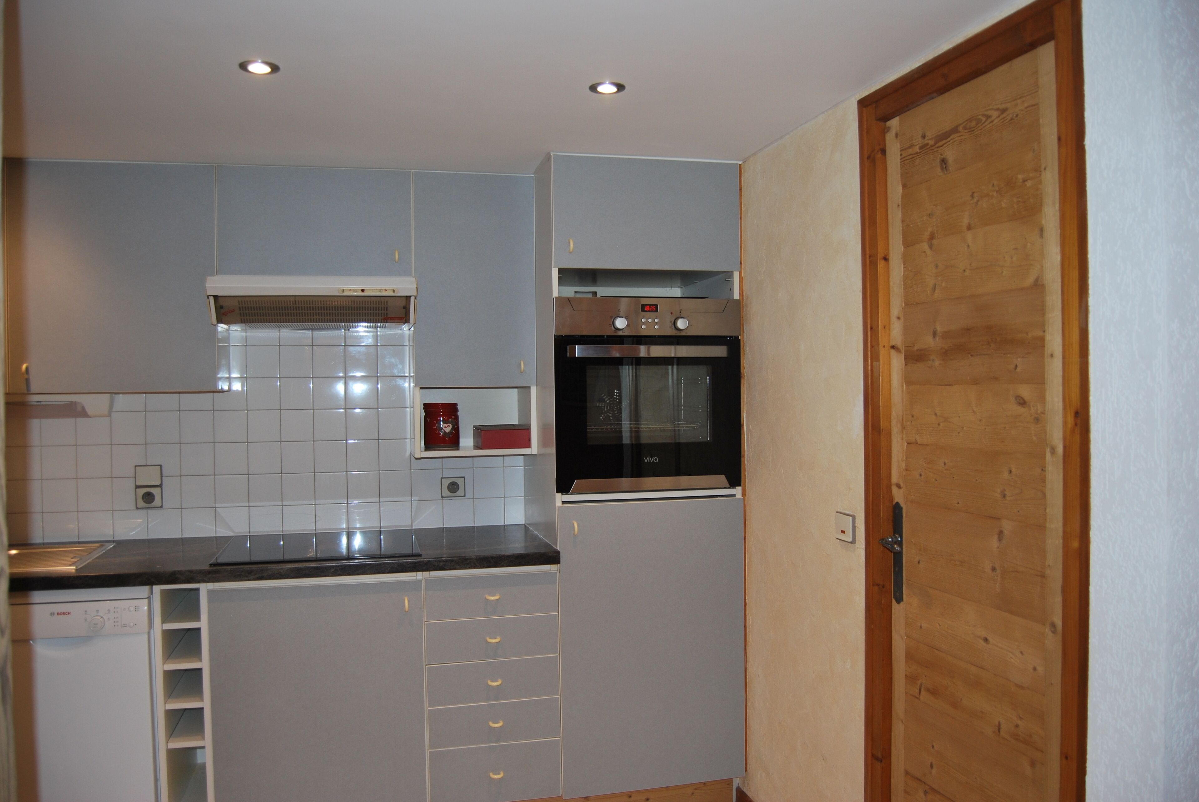A kitchen with white cabinets, a built-in oven, and a wooden door.
