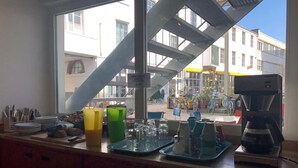 A kitchen counter with various items like plates, glasses, and a coffee maker. - Basel Backpack - Hostel (Basel)