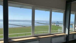 Una habitación con ventanas amplias que dan a un área verde y una masa de agua.