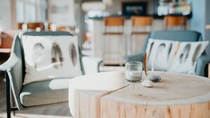 Un rincón acogedor con una mesa redonda de madera, un vaso de agua y objetos decorativos.