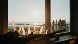 Vista a través de una ventana, con una estructura de madera en el exterior, posiblemente un muelle, y un cielo despejado.