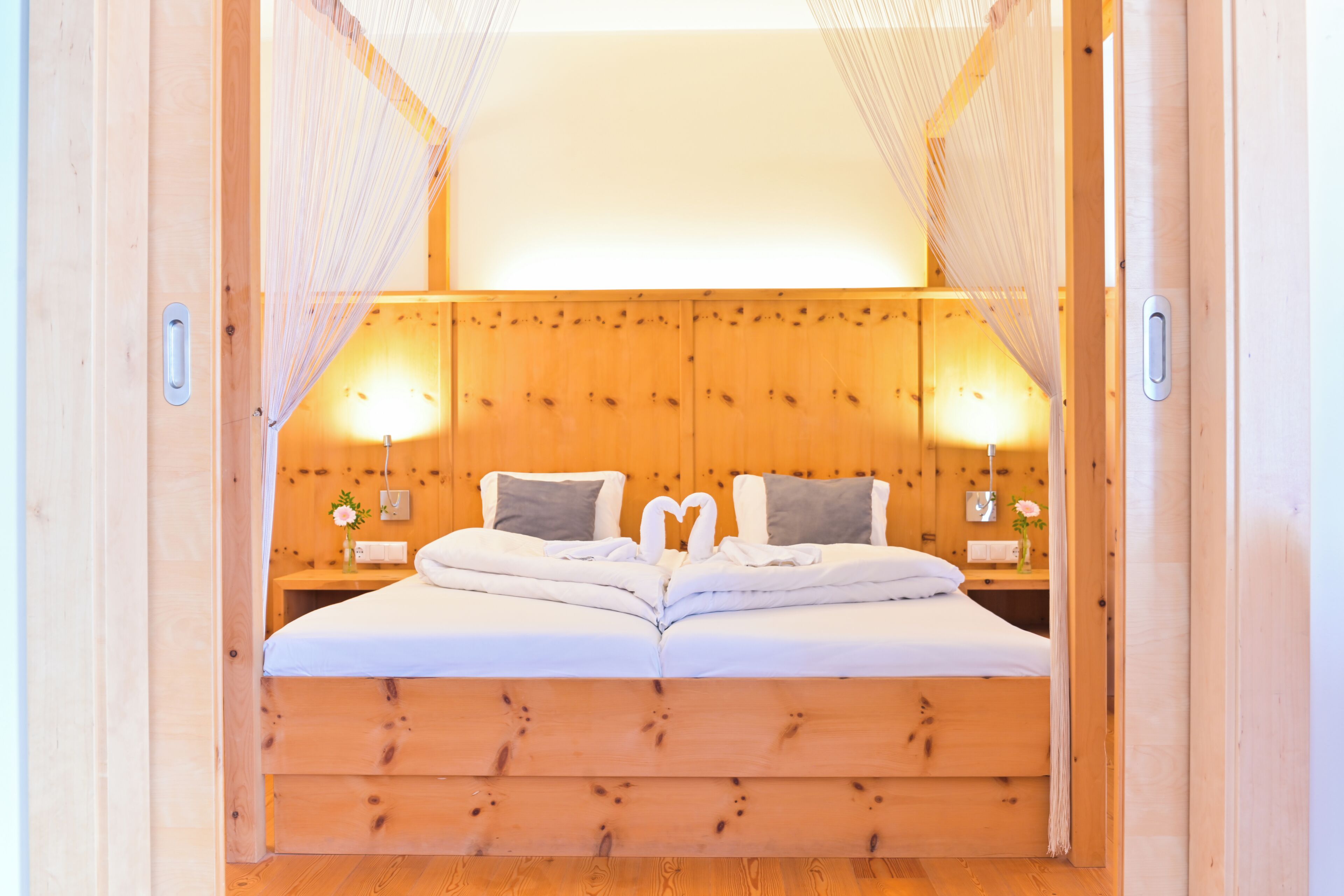 Una cama de madera con cabecera, dos mesitas de noche y dosel.
