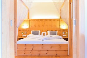 Een houten bed met hoofdeinde, twee nachtkastjes en een hemelbed.