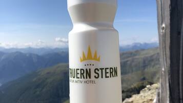 A water bottle with the logo and name of 'Tavern Stern' hotel, placed on a rock with a mountainous landscape in the background.