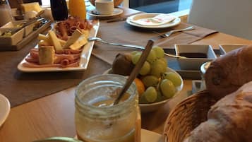 A breakfast table with various food items, including cheese, bread, and a bowl of grapes.