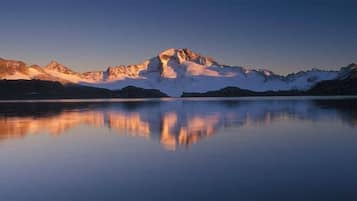 Ein Gebirgszug spiegelt sich in einem ruhigen See im Abenddämmerung.