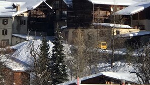 Une cabane en bois avec un toit en pente, entourée d’un paysage enneigé et d’arbres.