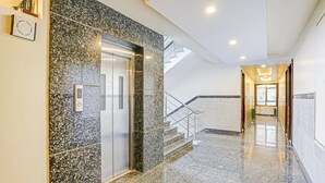 Eine moderne Hotelhalle mit Marmorboden, einer Glaselevator und einer Treppe.