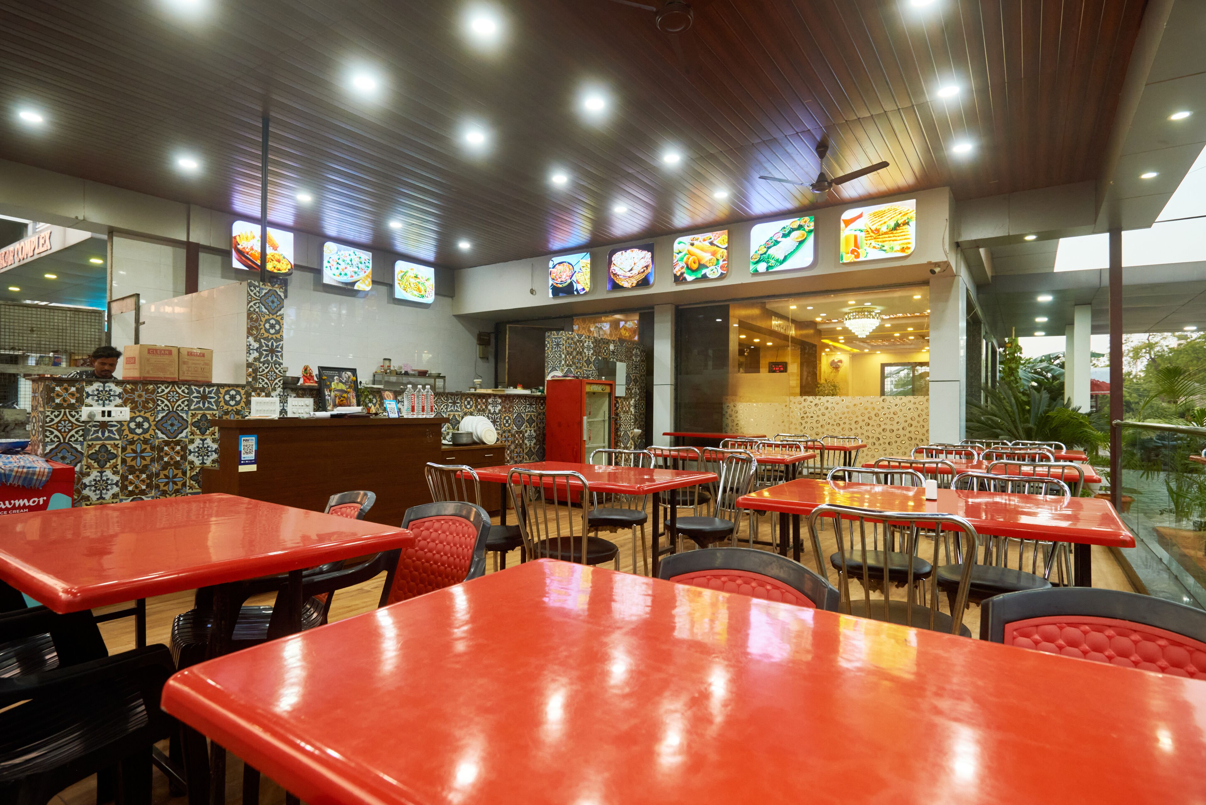 Un restaurante con mesas y sillas rojas, una pared con azulejos y una barra con un menú.