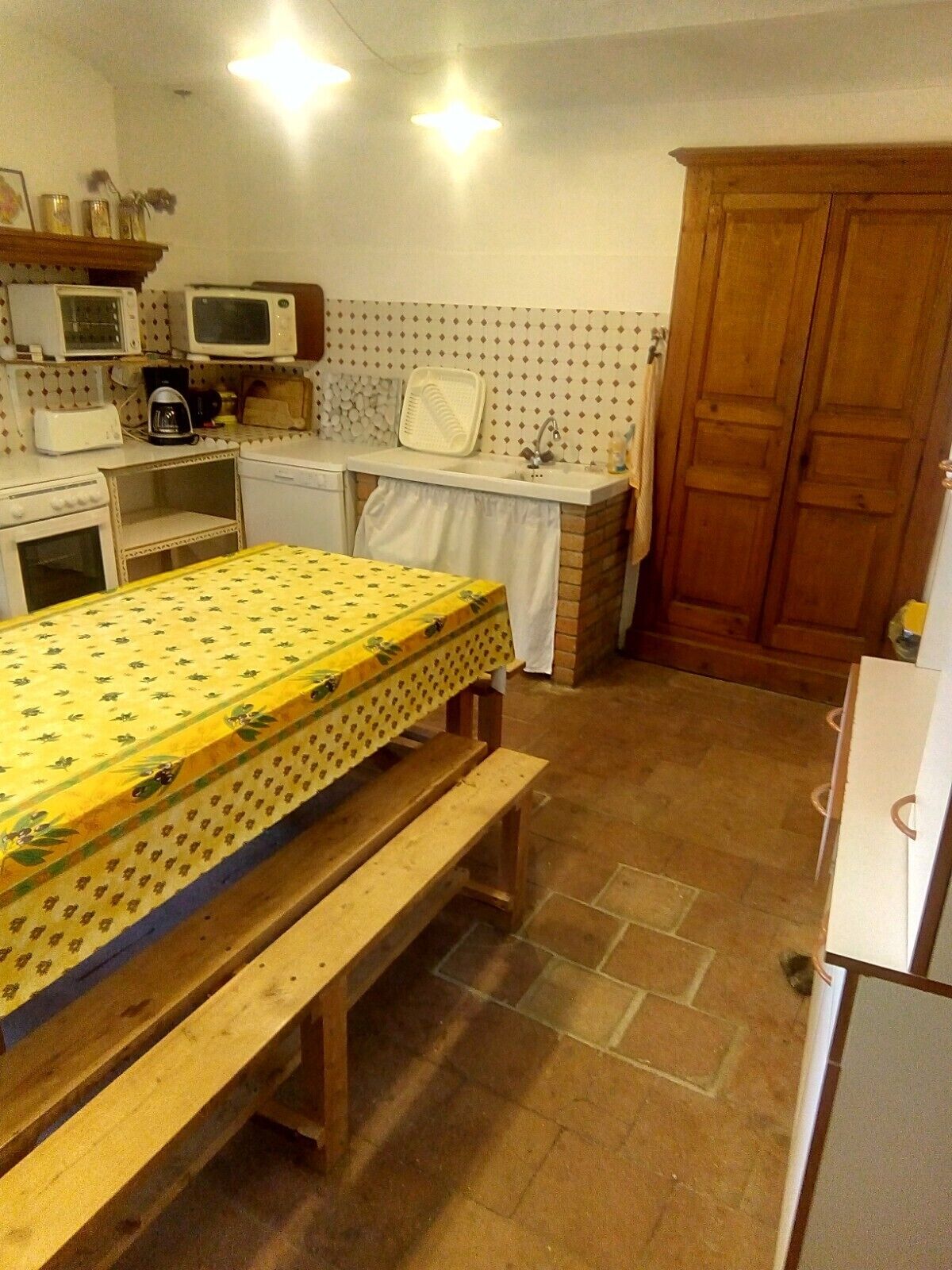 Una cocina compacta con una mesa y banco, y electrodomésticos básicos.