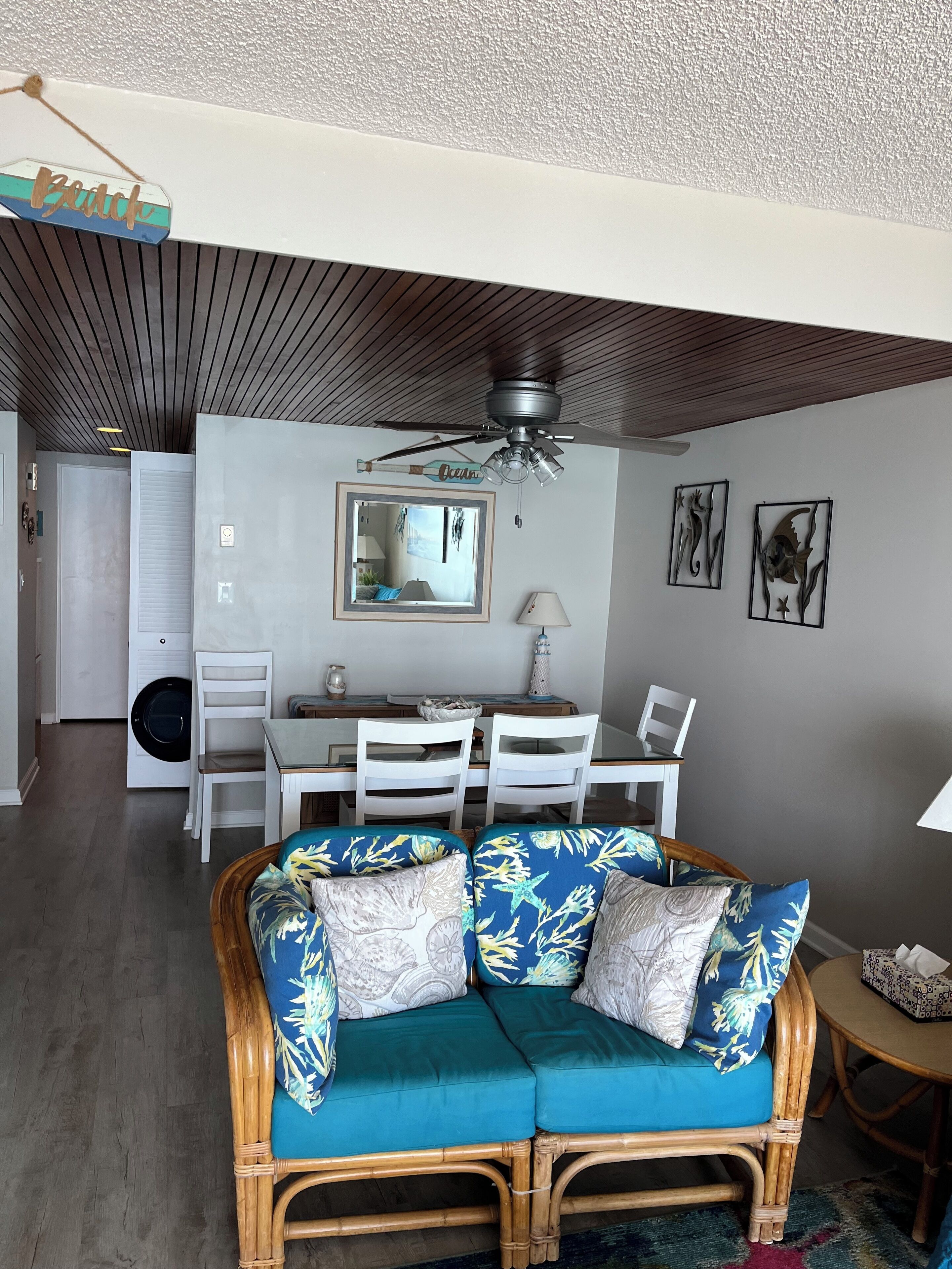 A living room with a sofa, dining table, chairs, and a ceiling fan.