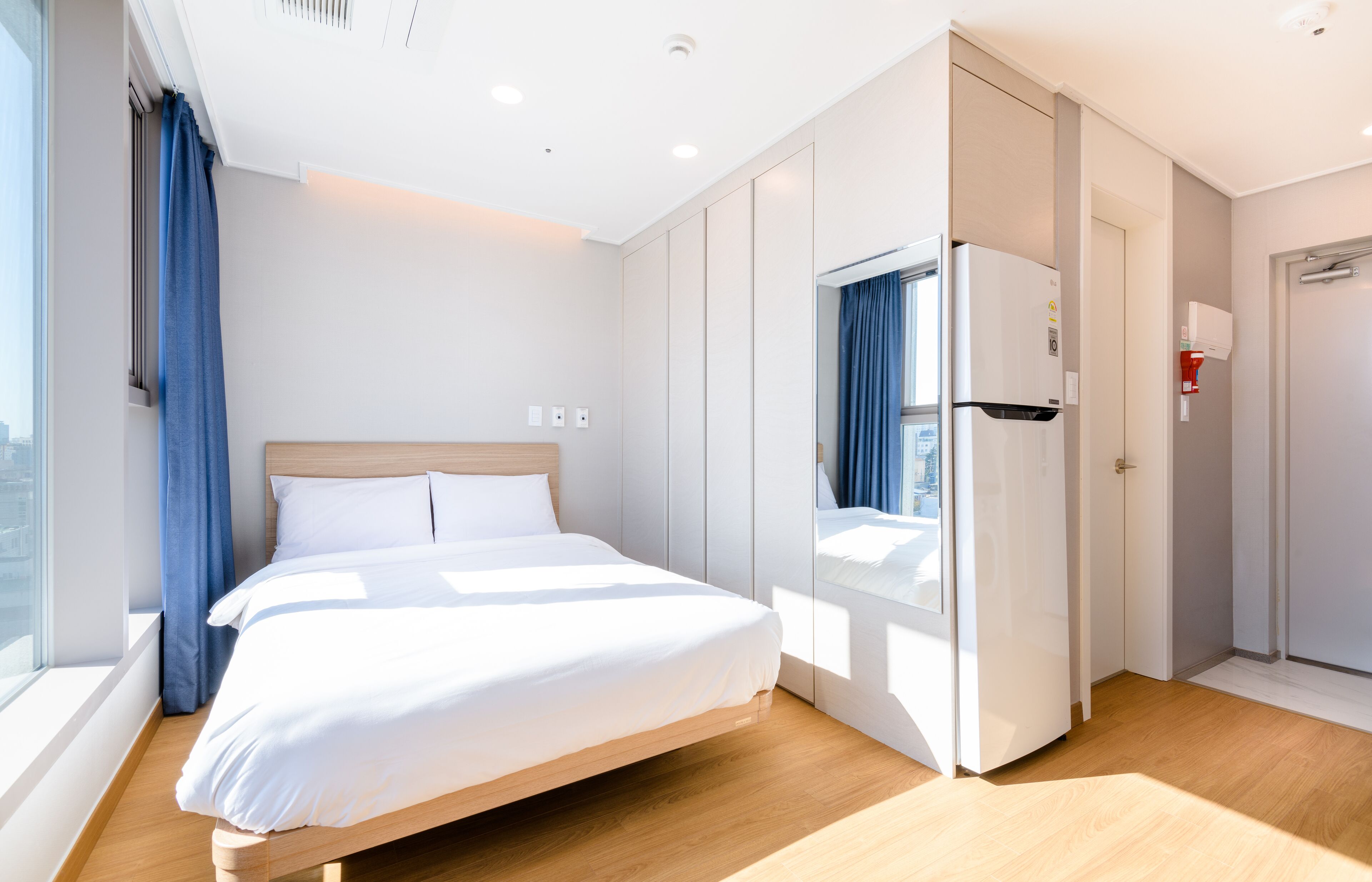 Ett modernt hotellrum med en stor säng, en garderob och utsikt över staden.