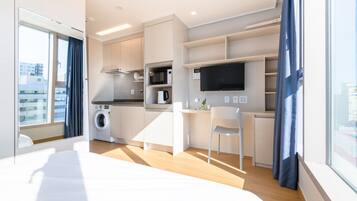 A modern kitchen with built-in appliances, a dining area, and a large window.