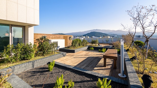 Un jardín en la azotea con terraza de madera, zona de estar y vistas a las montañas.