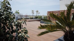 Un jardín en la azotea con suelo de madera, plantas en macetas y un muro de ladrillo.