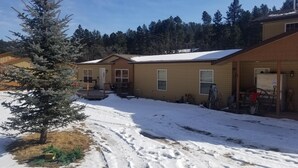 A two-story building with a snow-covered roof, a small porch, and a visible garage door. - American Pines Lodge, 5 miles from Mt. Rushmore (Keystone)