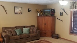 A living room with a brown sofa, a wooden coffee table, a cabinet, and a ceiling fan. - American Pines Lodge, 5 miles from Mt. Rushmore (Keystone)