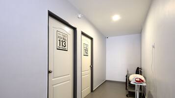 Un couloir avec deux portes, l’une portant l’inscription « Chambre n° 113 » et l’autre « Chambre n° 112 », les deux pouvant accueillir quatre personnes.